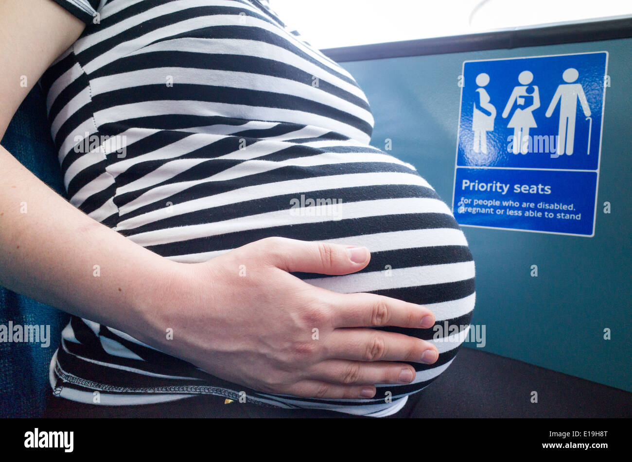 Pregnant woman sitting in a priority seat on a London bus, England, UK(02)