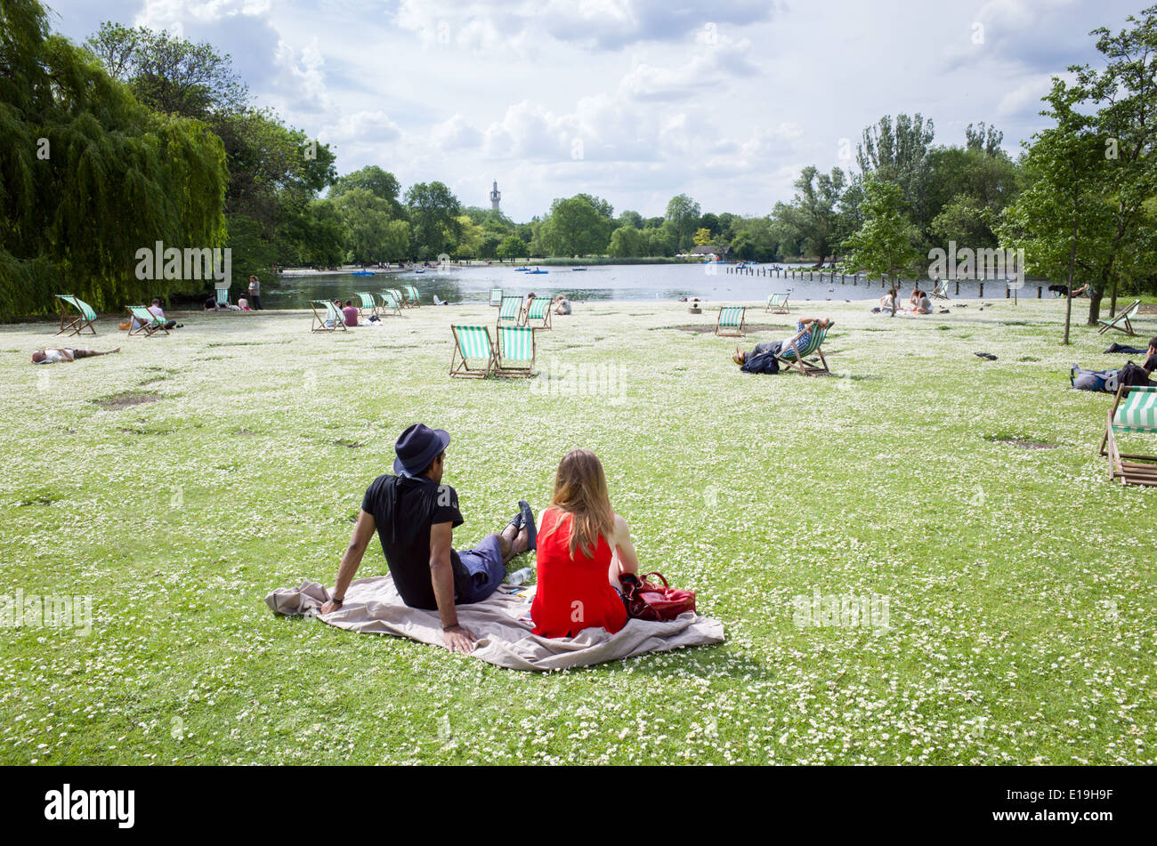Young couple sitting amongst the daisies in Regent's Park, London, England, UK Stock Photo