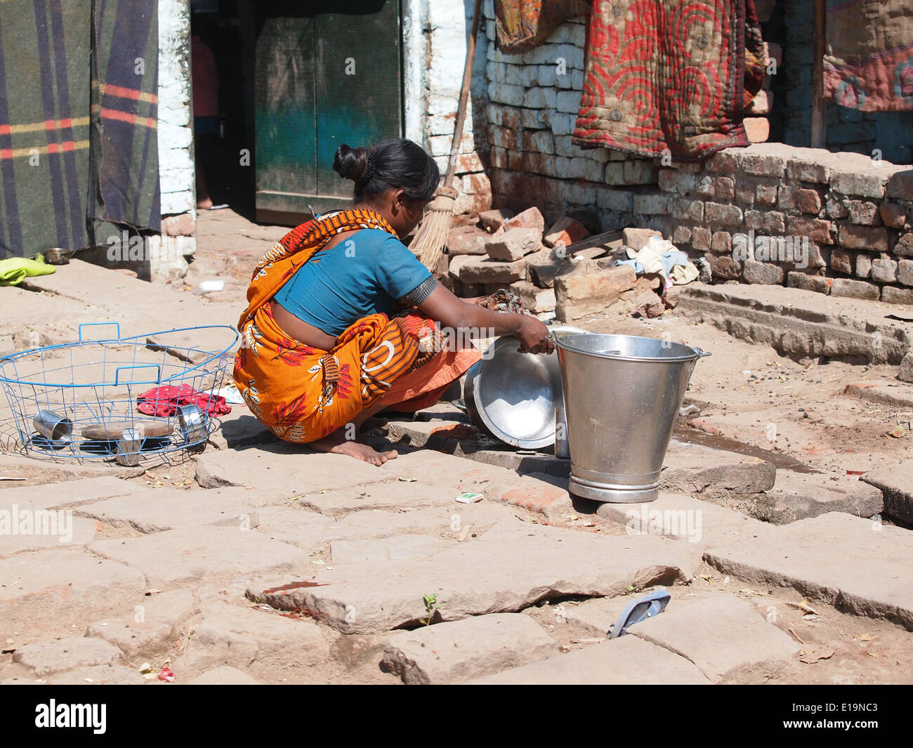 Indian woman washing dishes on the street  Stock Photo
