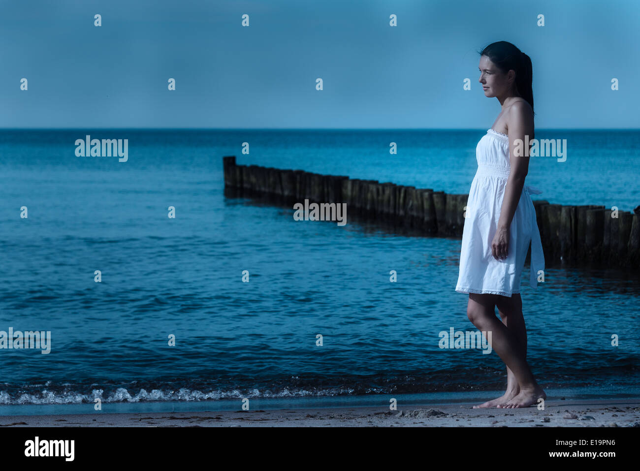 Beautiful meditative woman on a moonlit seashore Stock Photo
