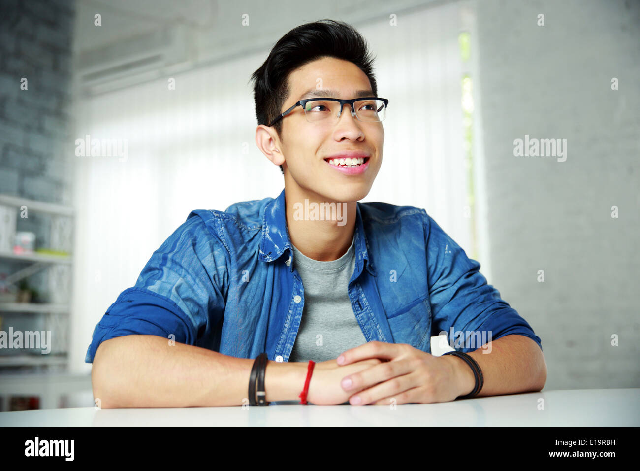 Young happy asian man sitting at the table Stock Photo