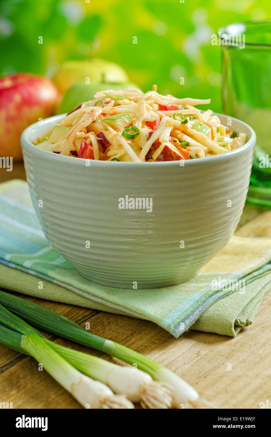 A bowl of delicious creamy apple coleslaw with cabbage, carrots, bell pepper and lemon. Stock Photo