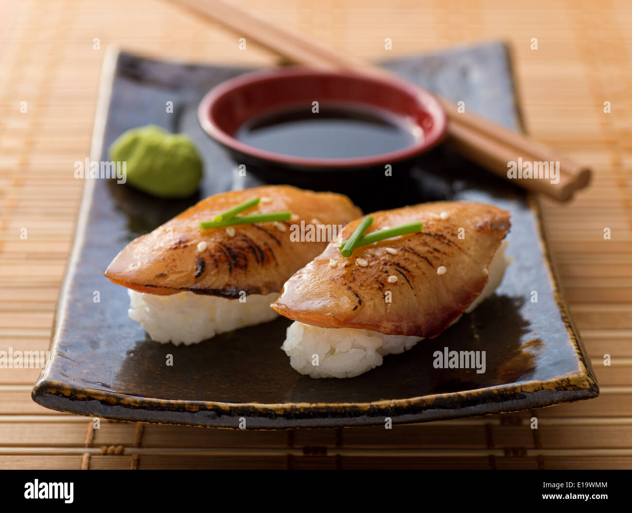 A delicious braised eel nigiri-zushi with wasabi paste and japanese soy garnished with green onion and sesame seeds. Stock Photo