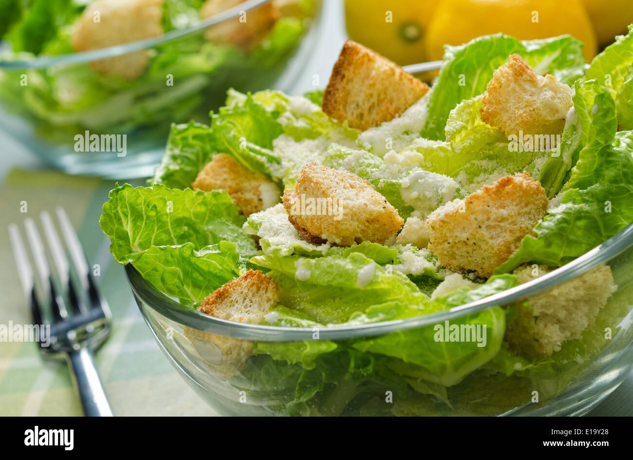 A bowl of crispy caesar salad with romaine lettuce, croutons, garlic, parmesan, and lemon. Stock Photo