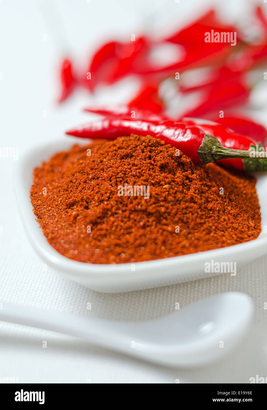 Ground cayenne pepper with whole peppers against a white canvas background. Stock Photo