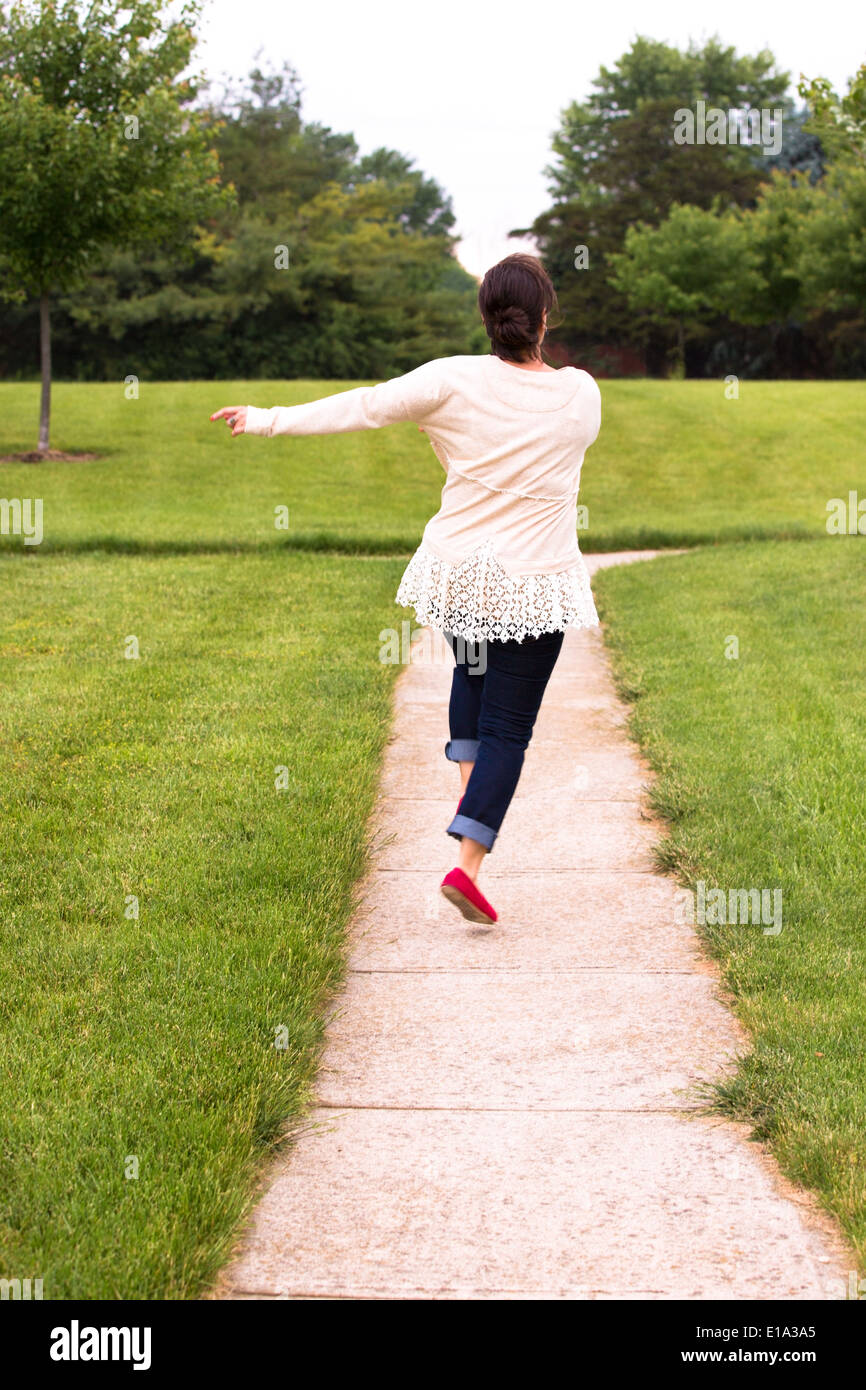 Happy lady cannot hide her feelings, shes is skipping happily with her arms  on the side, she is wearing lace shirt and jeans alo Stock Photo - Alamy