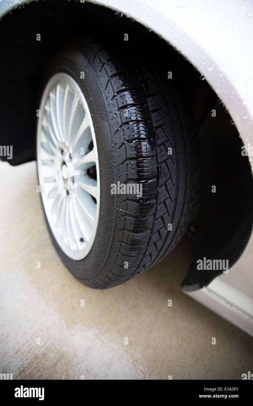 Wet automobile tire, on a concrete pavement, treads are showing clearly