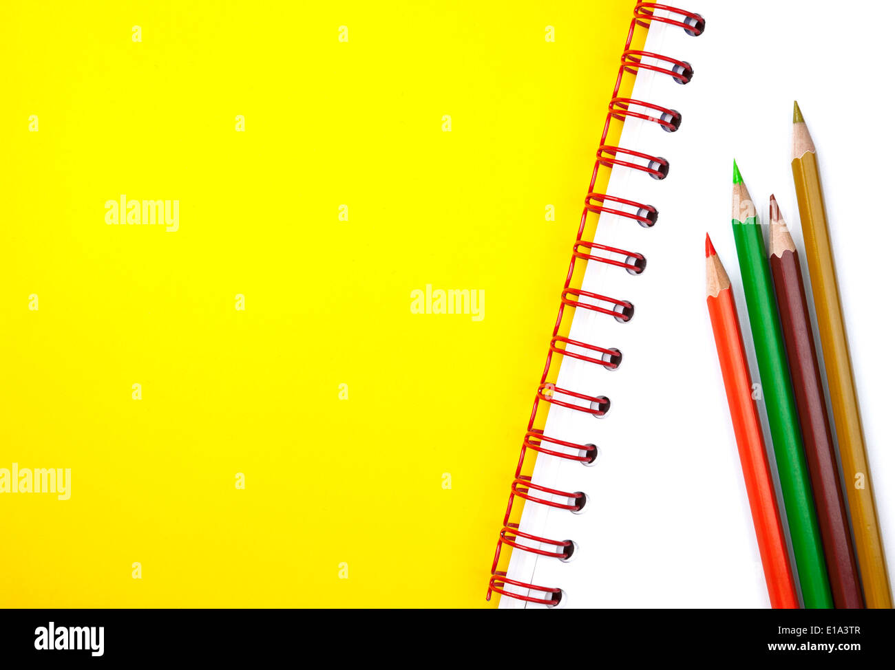 Four colorful pencils on white textbook with plenty of copy space to add text Stock Photo