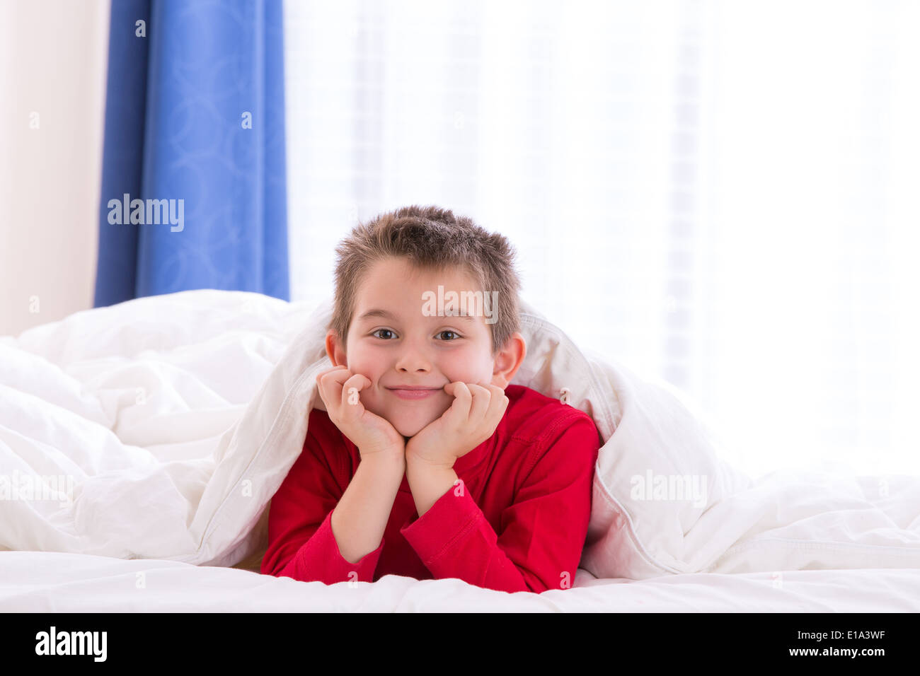 Close up portrait of a eight years old boy laying on the bed on looking