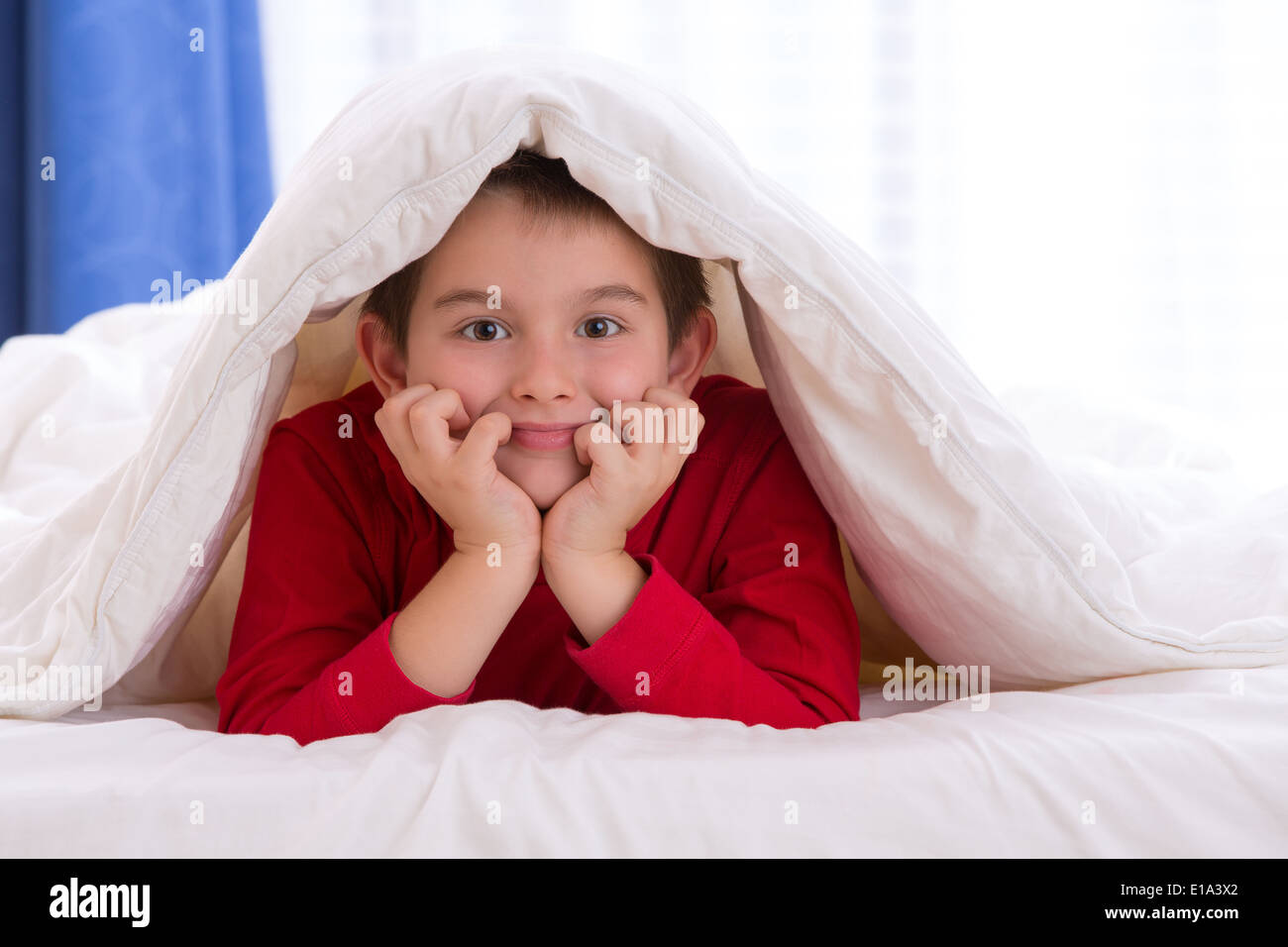 Close up portrait of a eight years old boy laying on the bed on looking