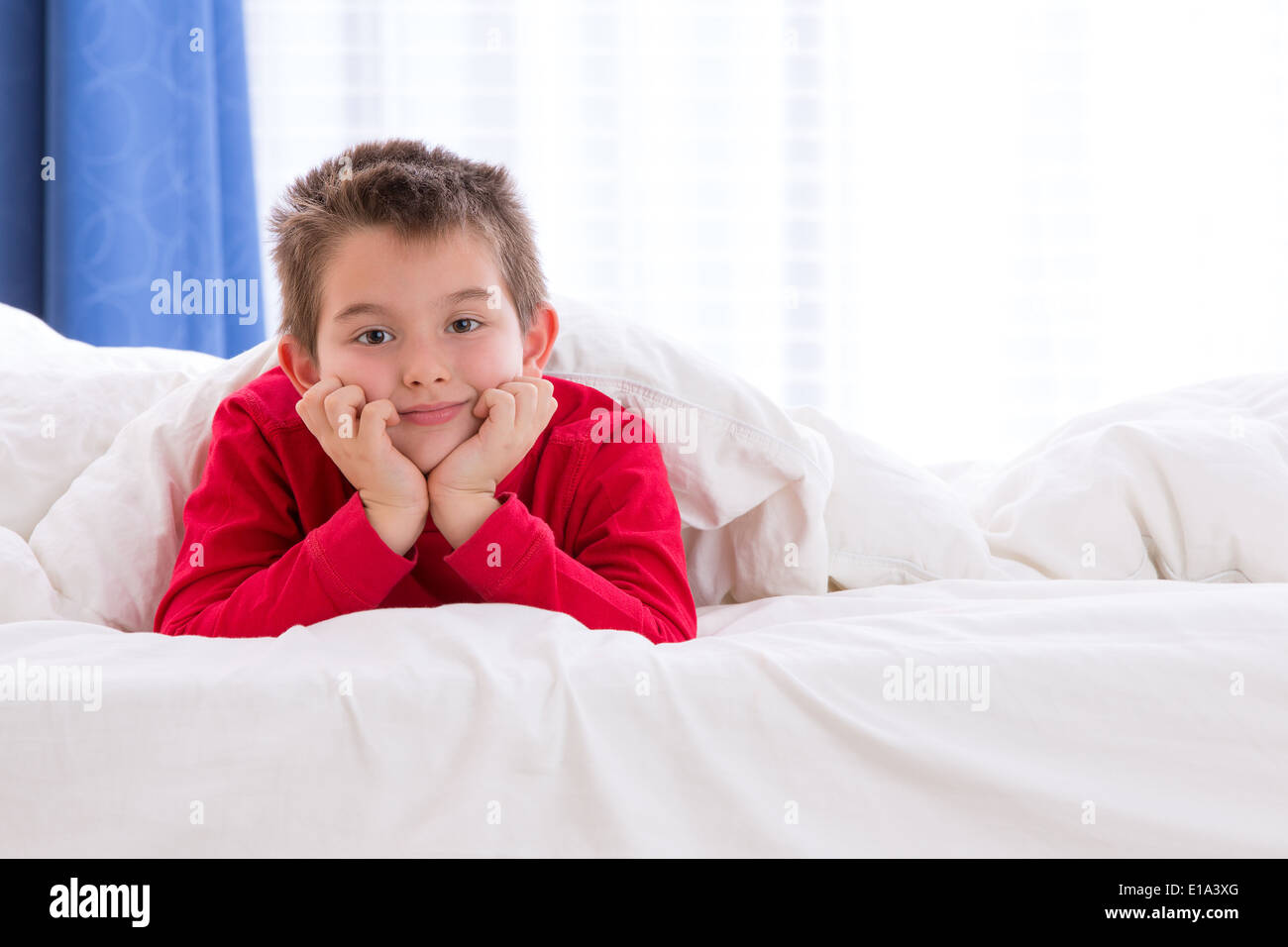 Close up portrait of a eight years old boy laying on the bed on looking
