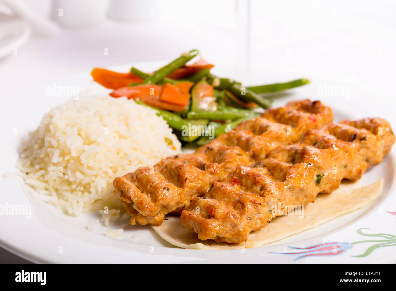 Chicken Adana kebap served with rice pilaf and green vegetables and