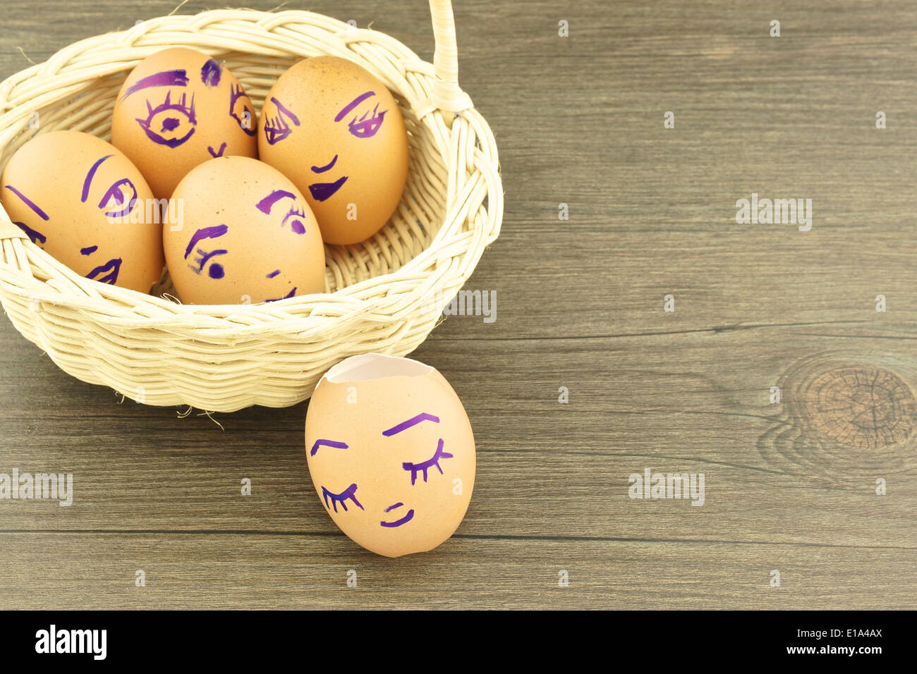 Happy and fun emoticons on empty eggshell in basket with wood background. Stock Photo
