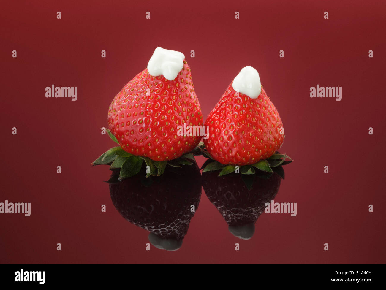 Two fresh Strawberries topped with natural thick Yogurt on red background Stock Photo