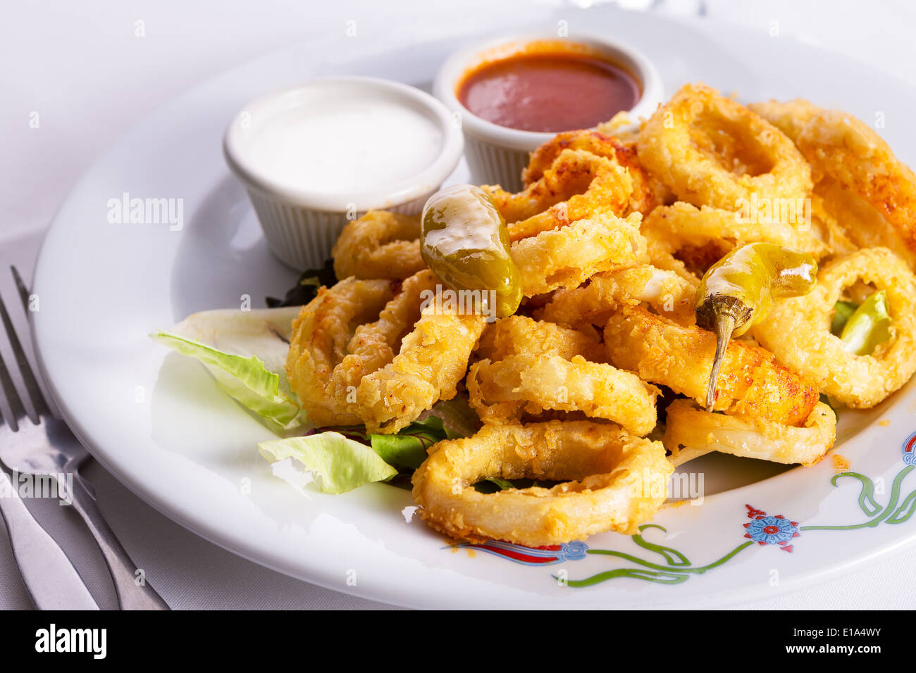 Deep fried breaded calamaris served with white and red sauce and topped