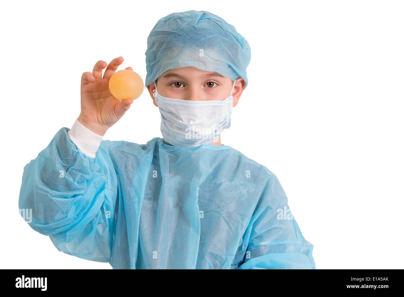 Third Grade elementary kid looking at you and showing his bouncy egg project in his doctor scrubs Stock Photo