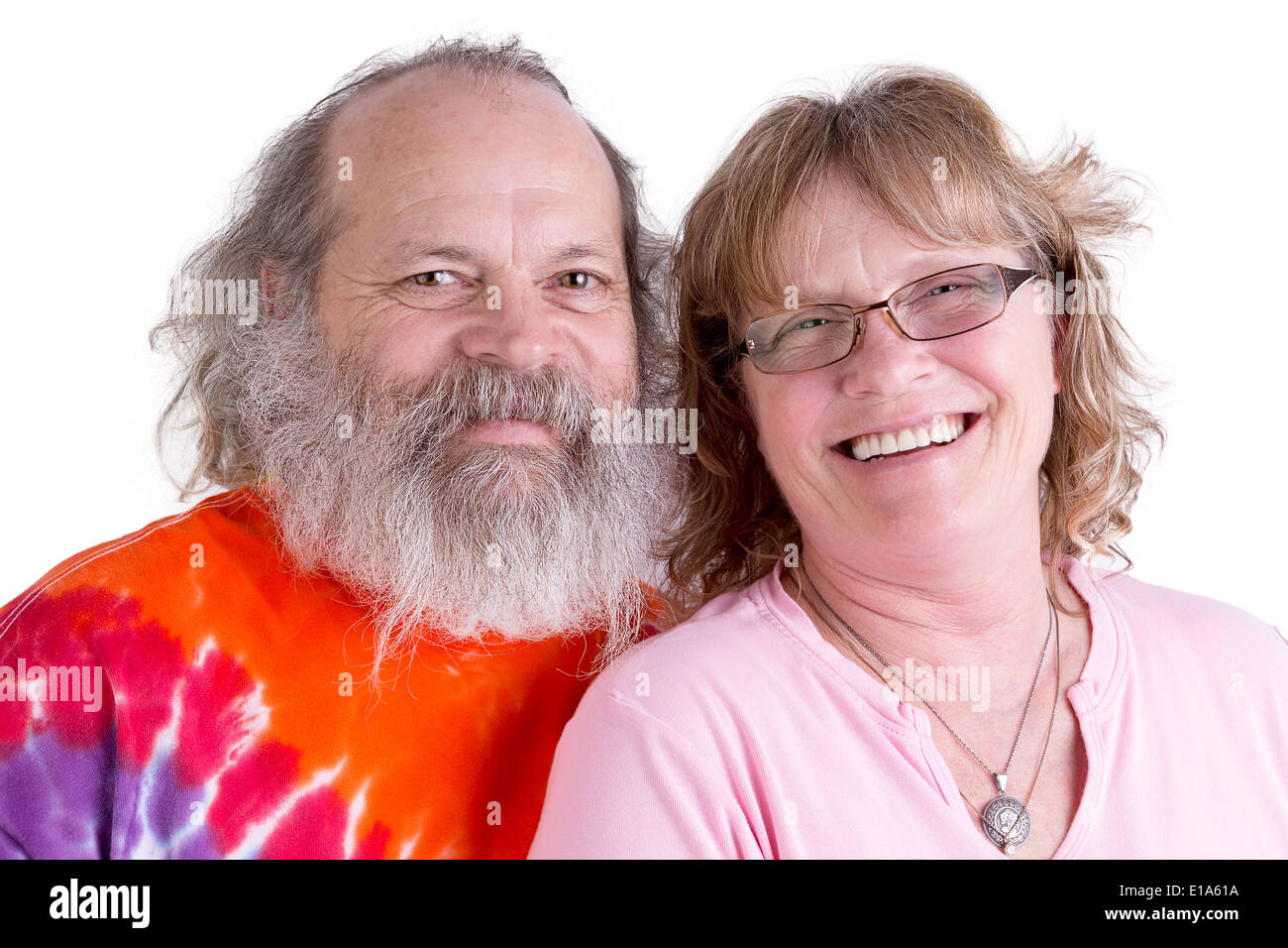 Happy baby boomer couple looking at you genuinly and smiling, male have long beard and colorful tye dye t-shirt, isolated Stock Photo
