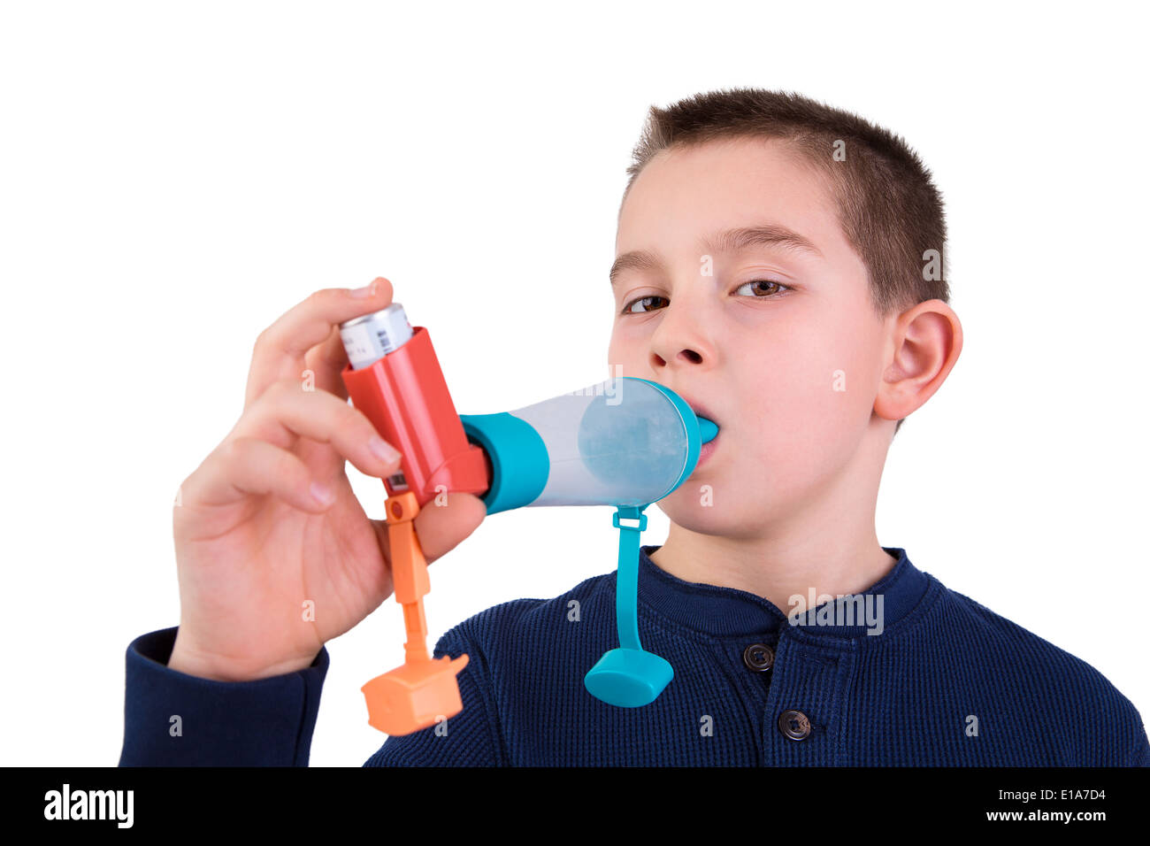 Nine years old kid with allergic asthma, inhaling his medication through spacer while looking at with his tired eyes Stock Photo