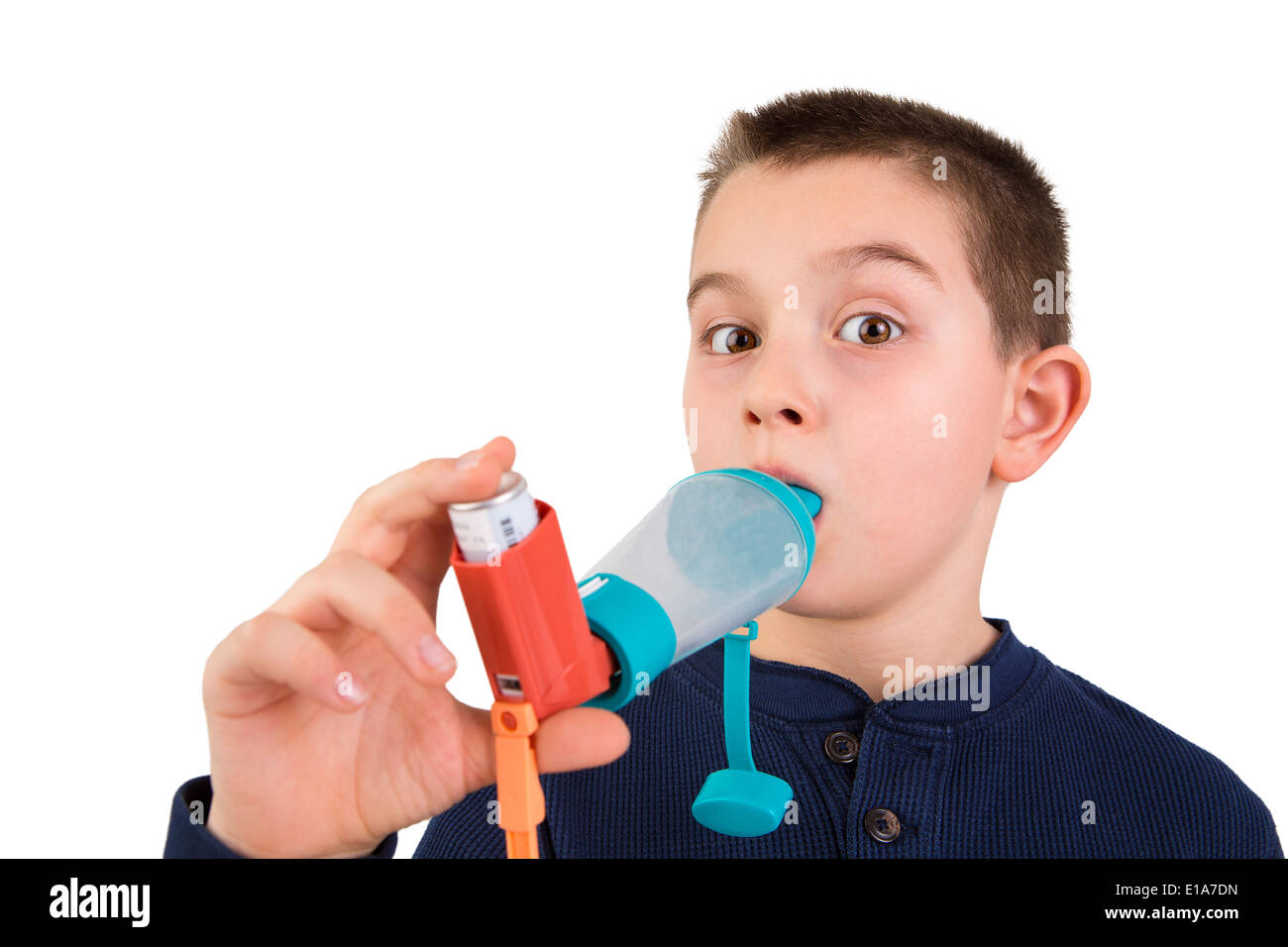 Nine years old kid with allergic asthma, inhaling his medication through spacer while looking at with his wide opened eyes perha Stock Photo