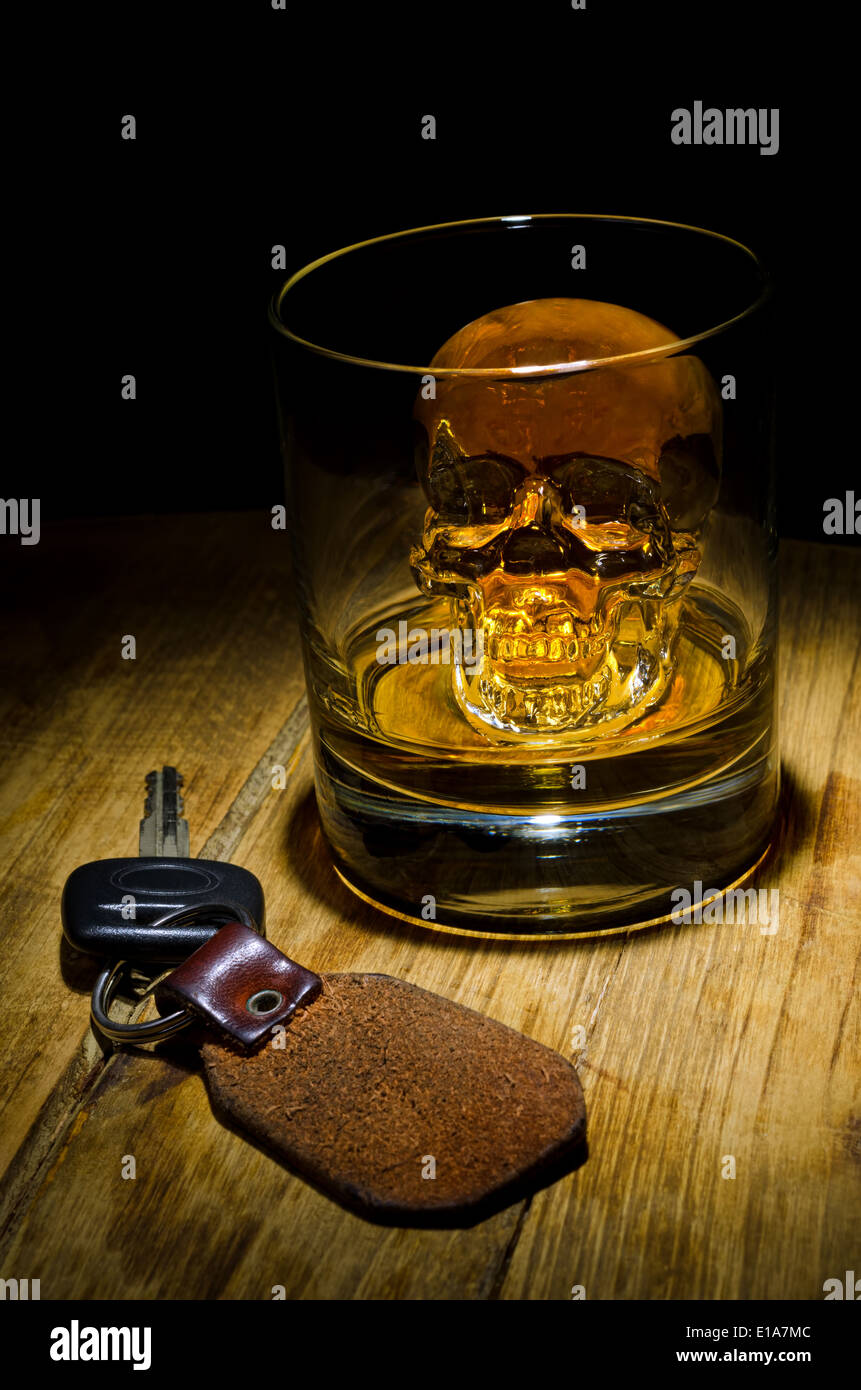 A glass of whiskey with a skull ice cube with car keys. Stock Photo