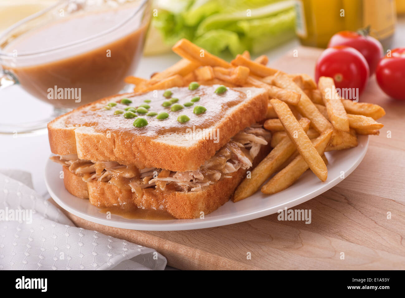 A delicious hot turkey sandwich with gravy, green peas, and french