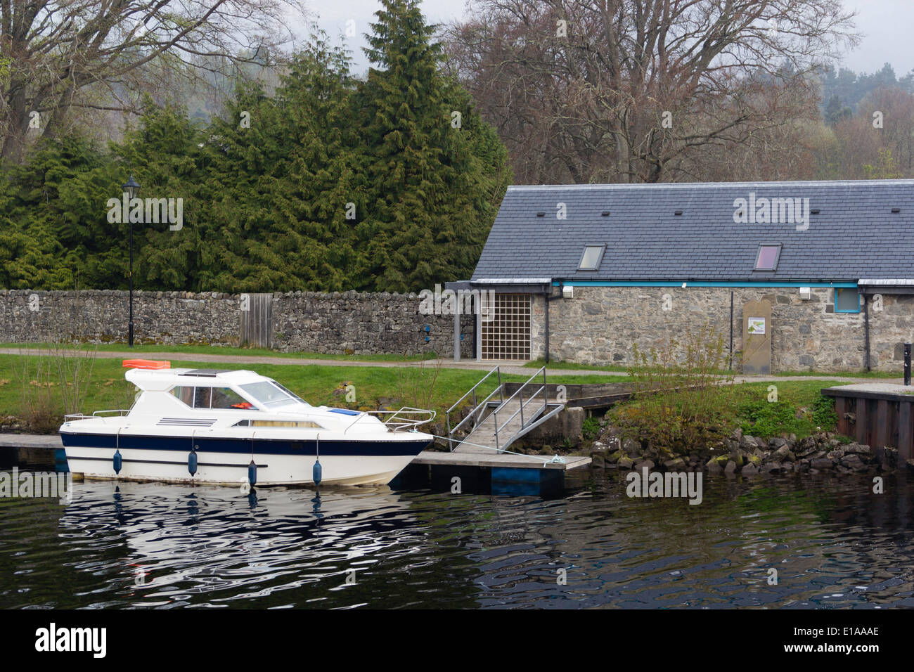 Small white yacht in the water of the Caledonian Canal in Fort Augustus. A number of people do boating on the canal. Stock Photo