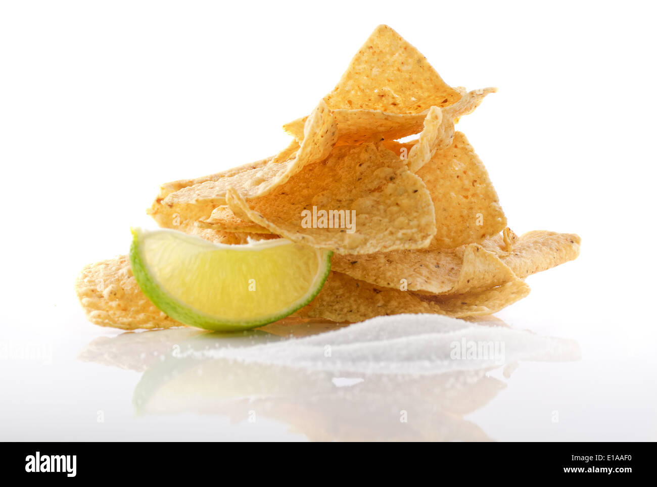 A stack of nachos with lime and sea salt against a white background. Stock Photo