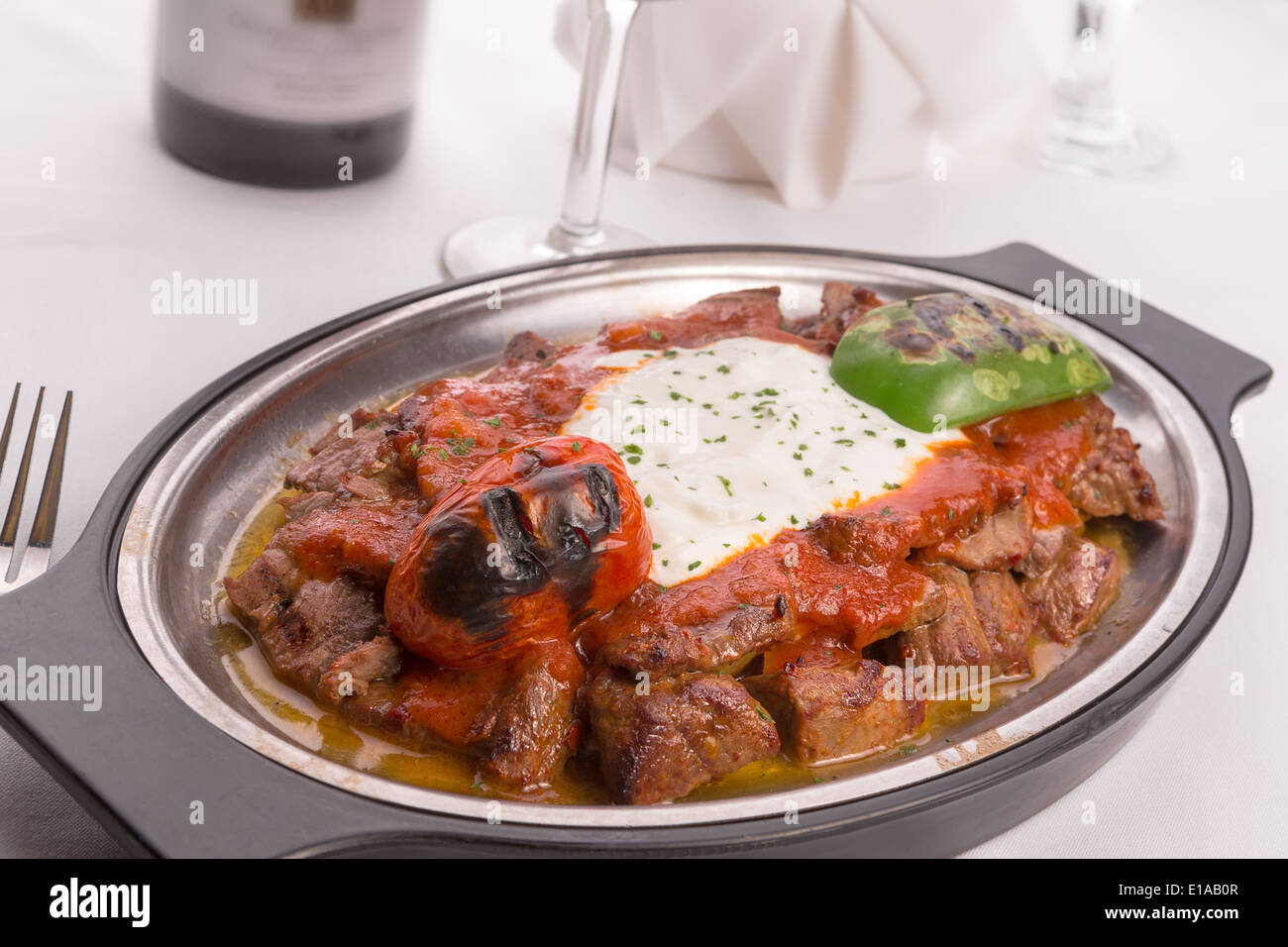Traditional Turkish Bursa iskender kebap doner served with special red sauce and yogurt in the middle, garnished with grilled Stock Photo