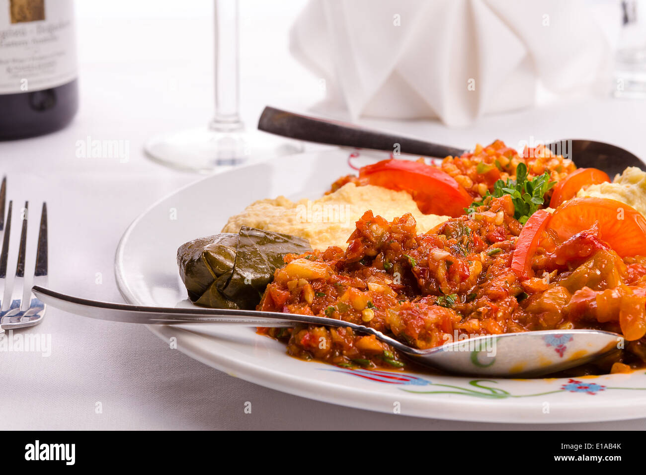 Appetizer sampler plate with Turkish ezme, hummus, babaganoush and dolma served with couple spoons Stock Photo