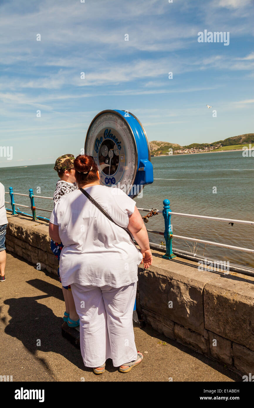 Over weight woman, standing at outdoor scales on Llandudno pier with a friend, Llandudno, Wales, United Kingdom. Stock Photo