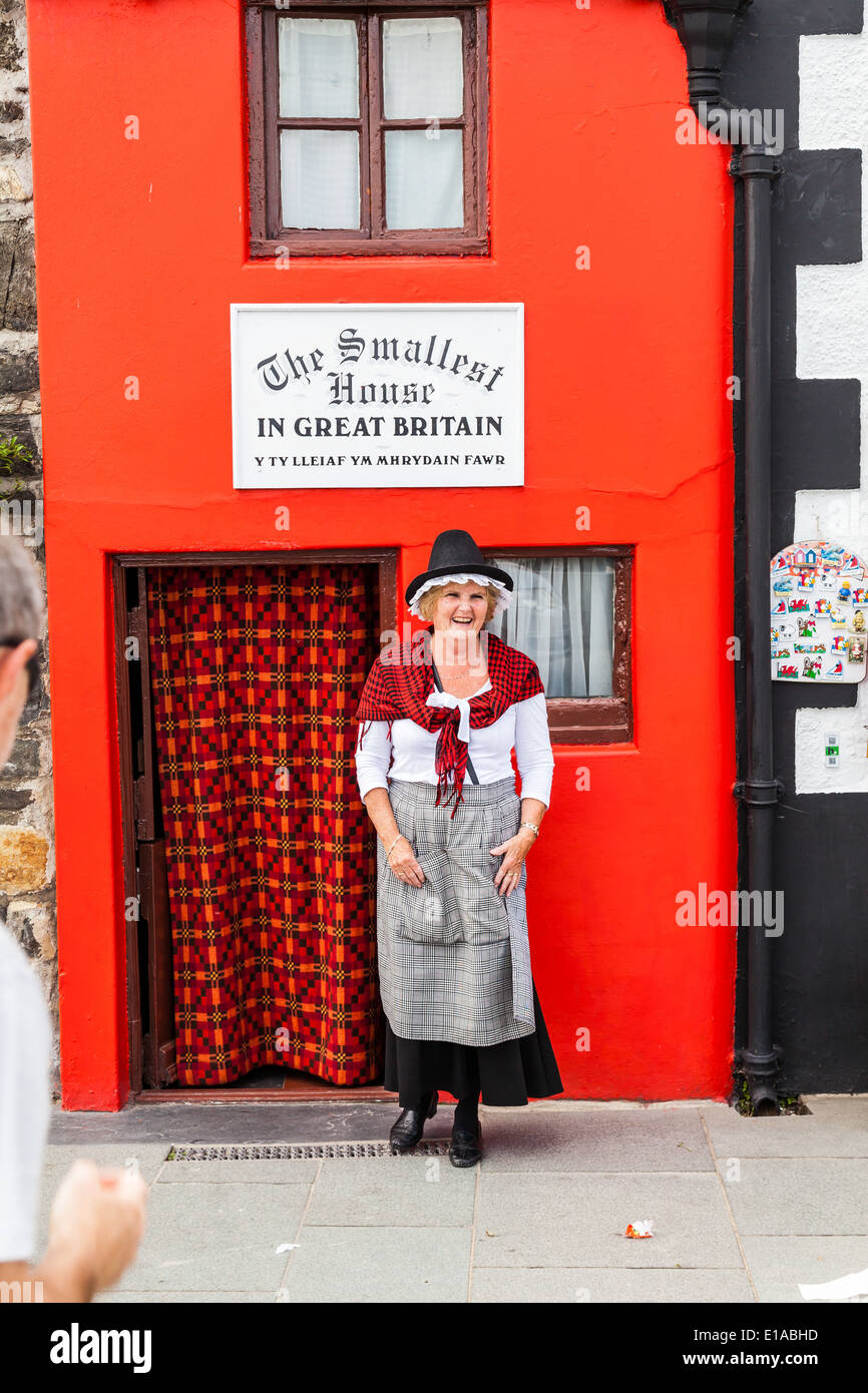 Conway Wales; Local woman in traditional welsh dress, laughing and posing for photographs, outside the smallest house in Britain Stock Photo