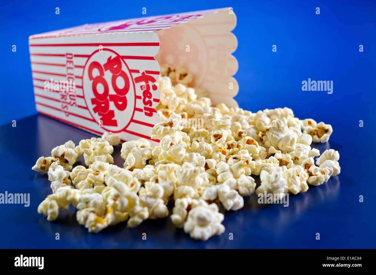 Freshly popped popcorn against a vivid blue background. Stock Photo