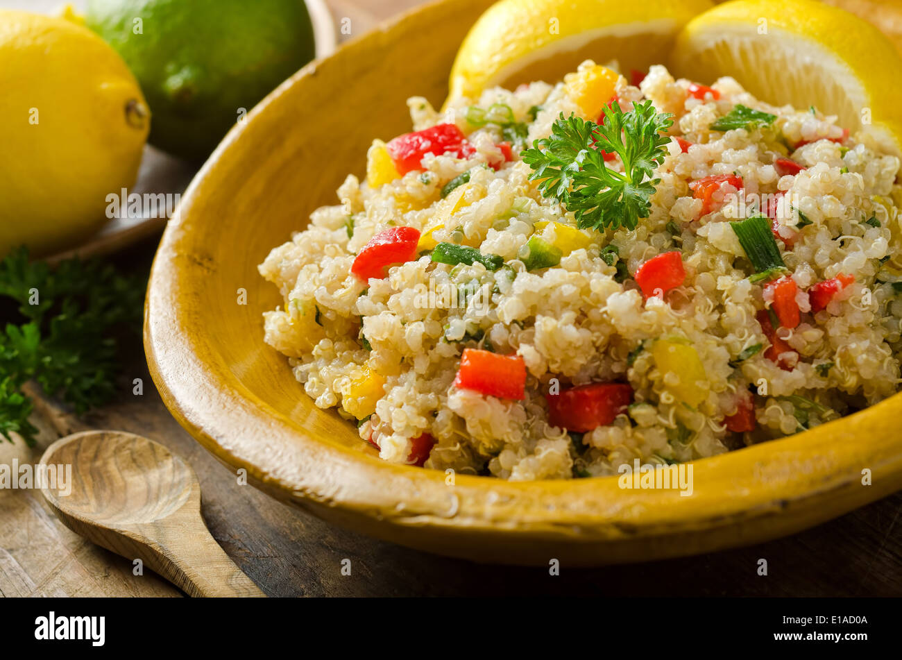A healthy delicious quinoa salad with lemon, lime, red pepper, yellow pepper, green onion, and parsley. Stock Photo