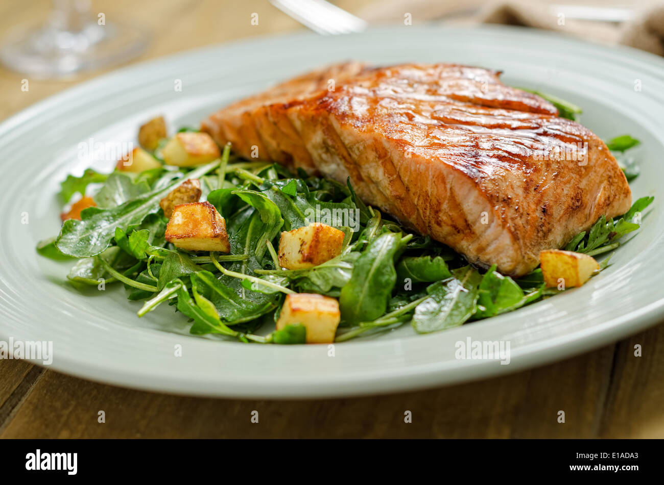 Grilled salmon with roasted potato and arugula salad. Stock Photo