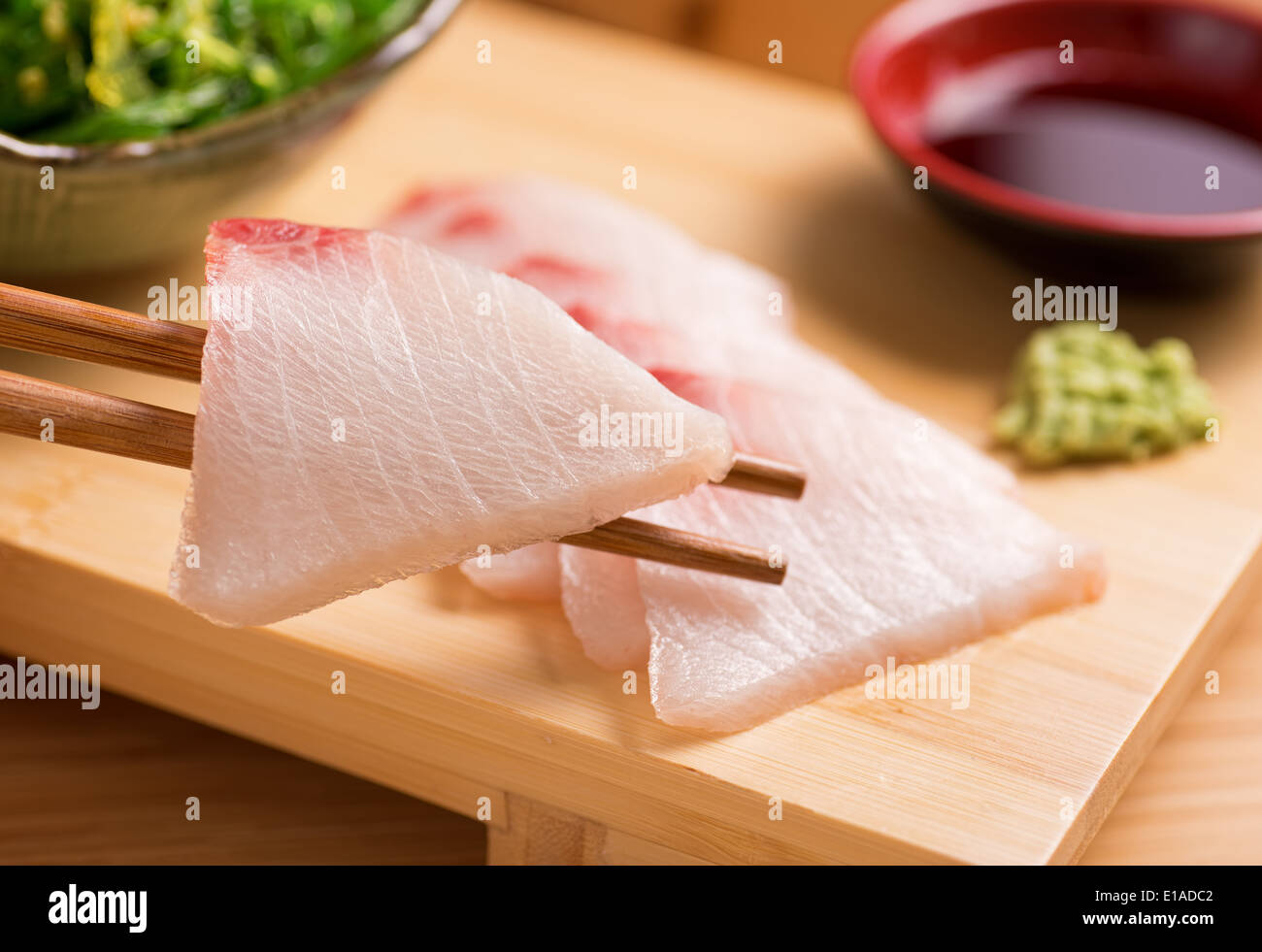 A delicious fresh white fish sashimi served with wasabi paste, japanese soy, and seaweed salad. Stock Photo