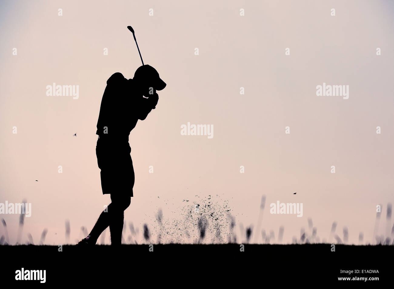 Silhouette of golf player taking a shot at sunset Stock Photo