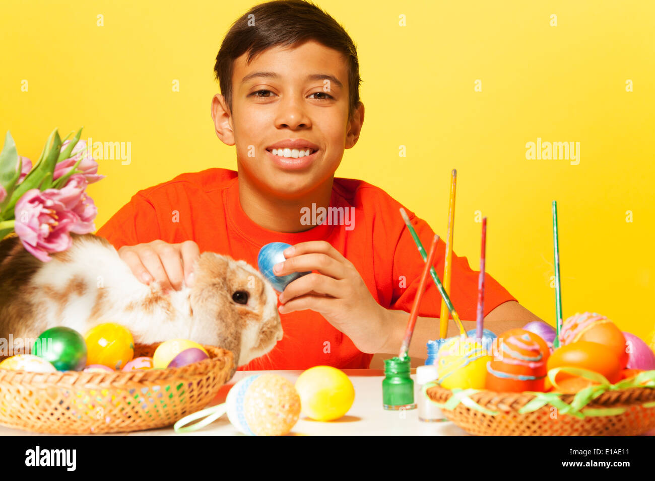Happy boy with Easter eggs and rabbit on  table Stock Photo