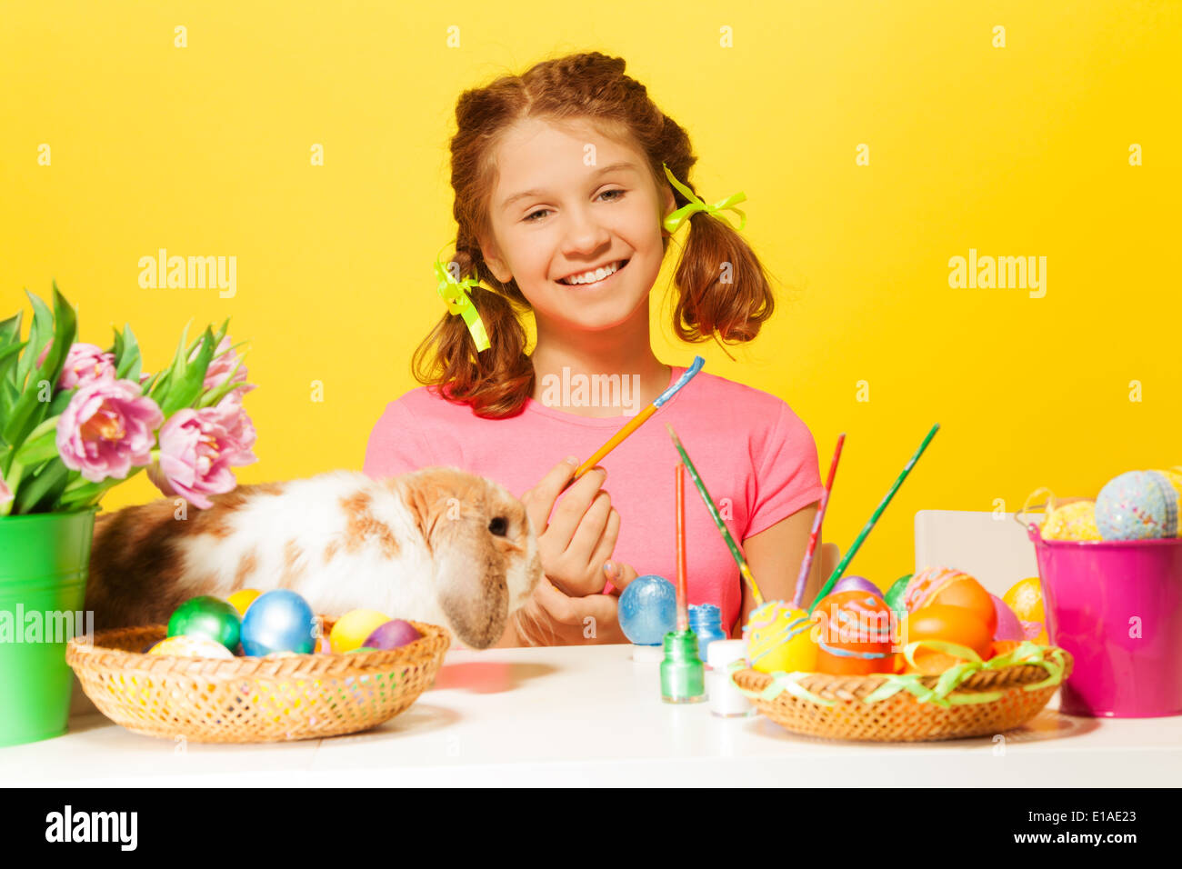 Girl paints Easter eggs with rabbit on the table Stock Photo