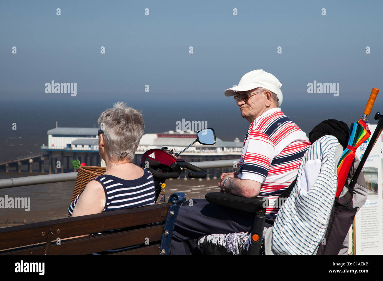 Elderly man sits in mobility scooter looking out on Cromer coastline Stock Photo