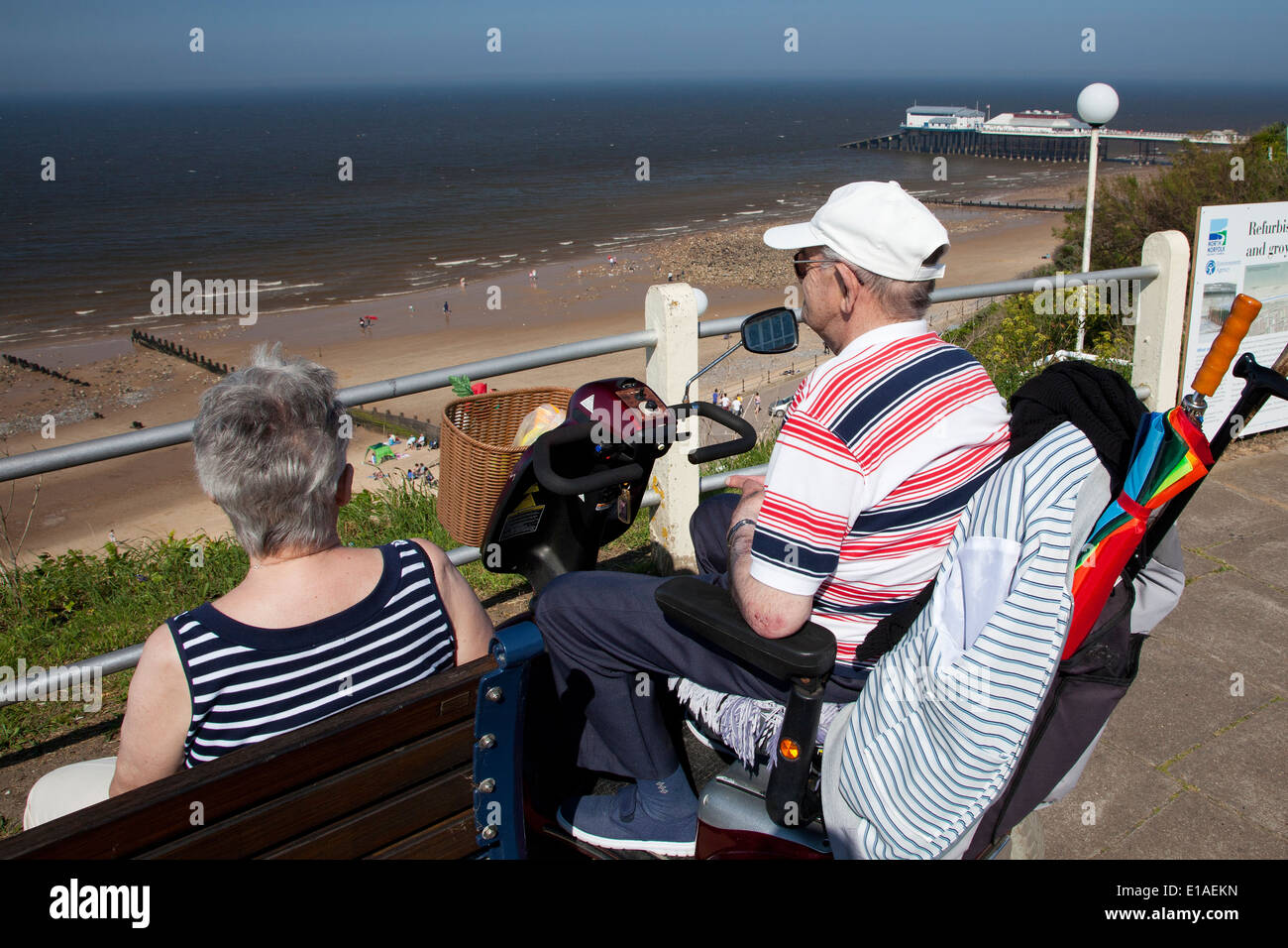 Elderly man sitting in mobility scooter on Cromer clifftop promenade Stock Photo