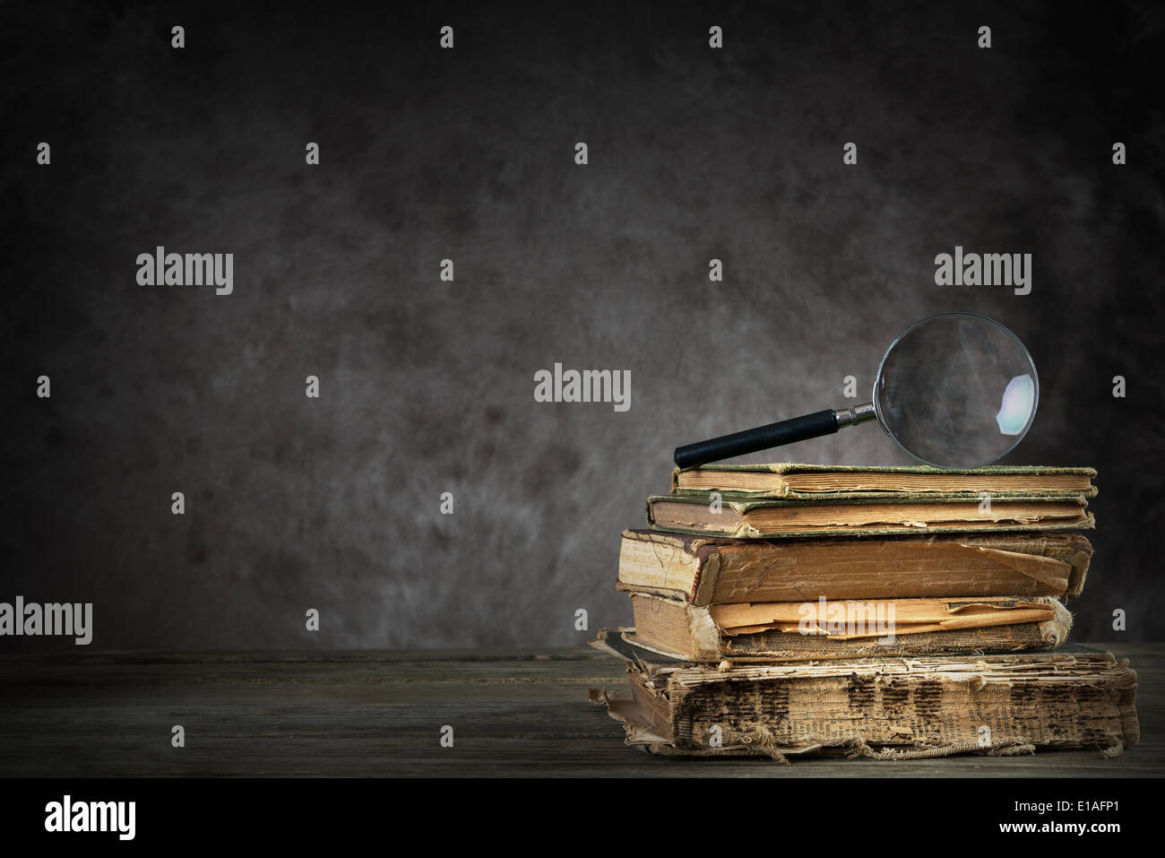 pile of old antique and yellowed books with a magnifier Stock Photo