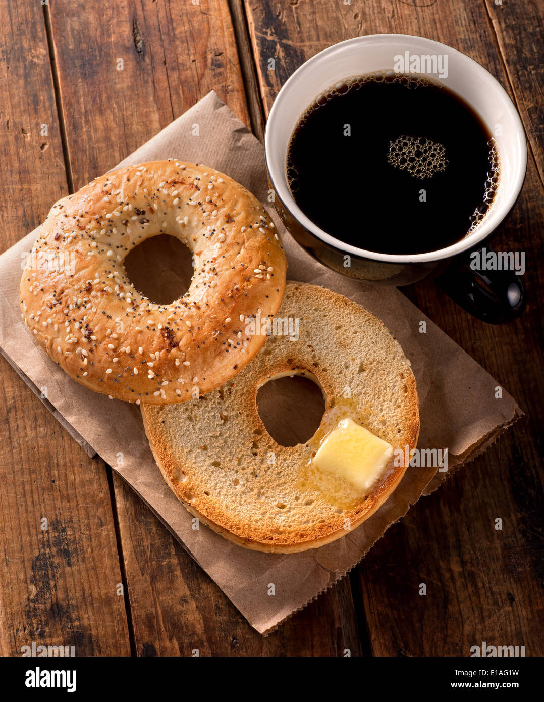 A delicious toasted everything bagel with melted butter and black coffee. Stock Photo