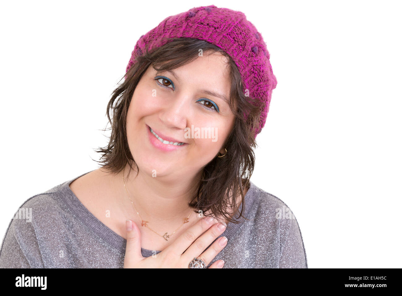 Woman wearing a knitted purple beanie showing her heartfelt gratitude holding her hand to her chest with a lovely sincere smile Stock Photo
