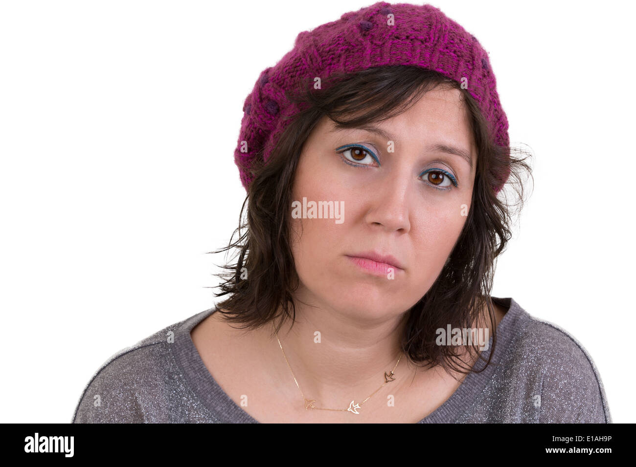 Woman wearing a purple beanie looking at the camera with a mournful woebegone expression and dull eyes, isolated on white Stock Photo