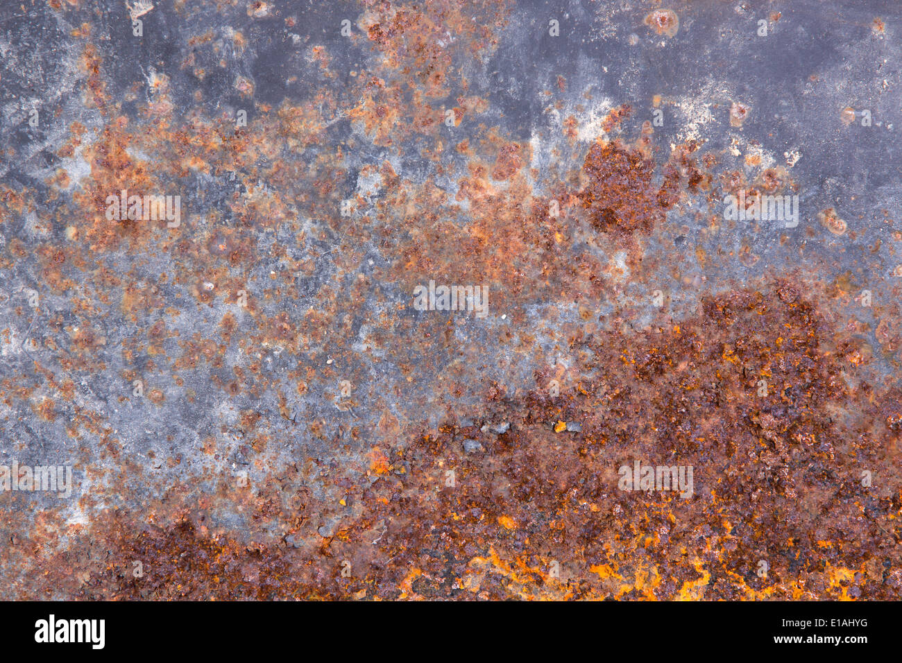 Grungy old rusting metal surface with pitted flaking blue paint and red