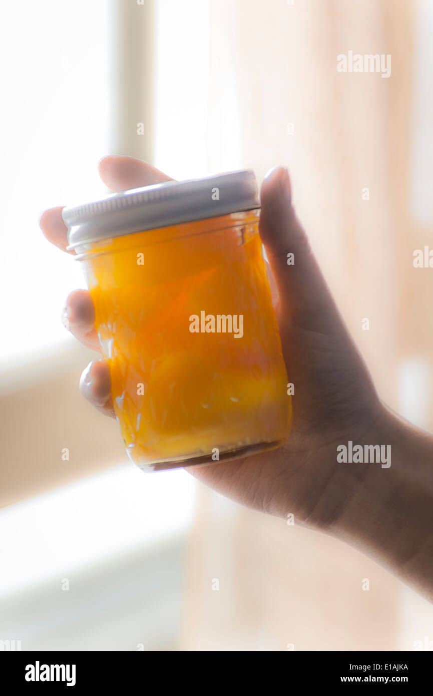 Womans Hand Holding A Jar Of Peaches By Window Stock Photo