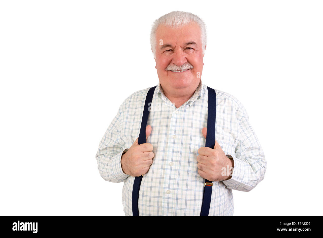 Confident senior grey-haired man with a mustache and beaming friendly smile holding his suspenders or braces, upper body isolat Stock Photo