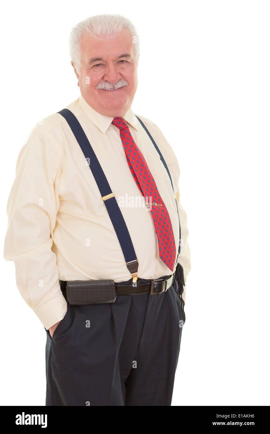 Genial senior businessman in braces standing in a confident relaxed pose with his hands in his pocket smiling with suspenders Stock Photo