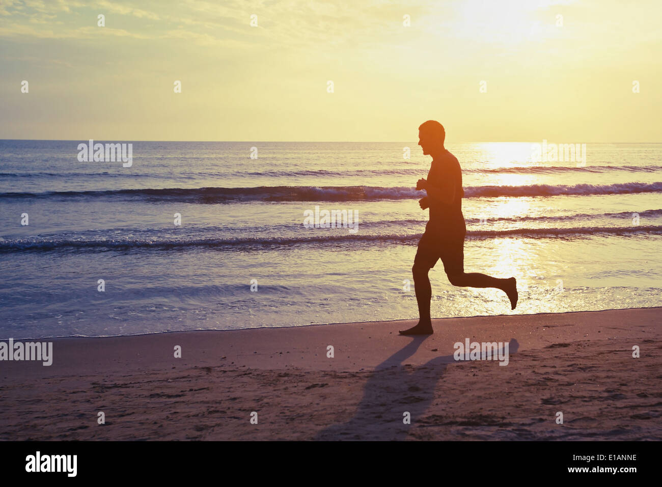 healthy lifestyle, silhouette of runner on the beach Stock Photo