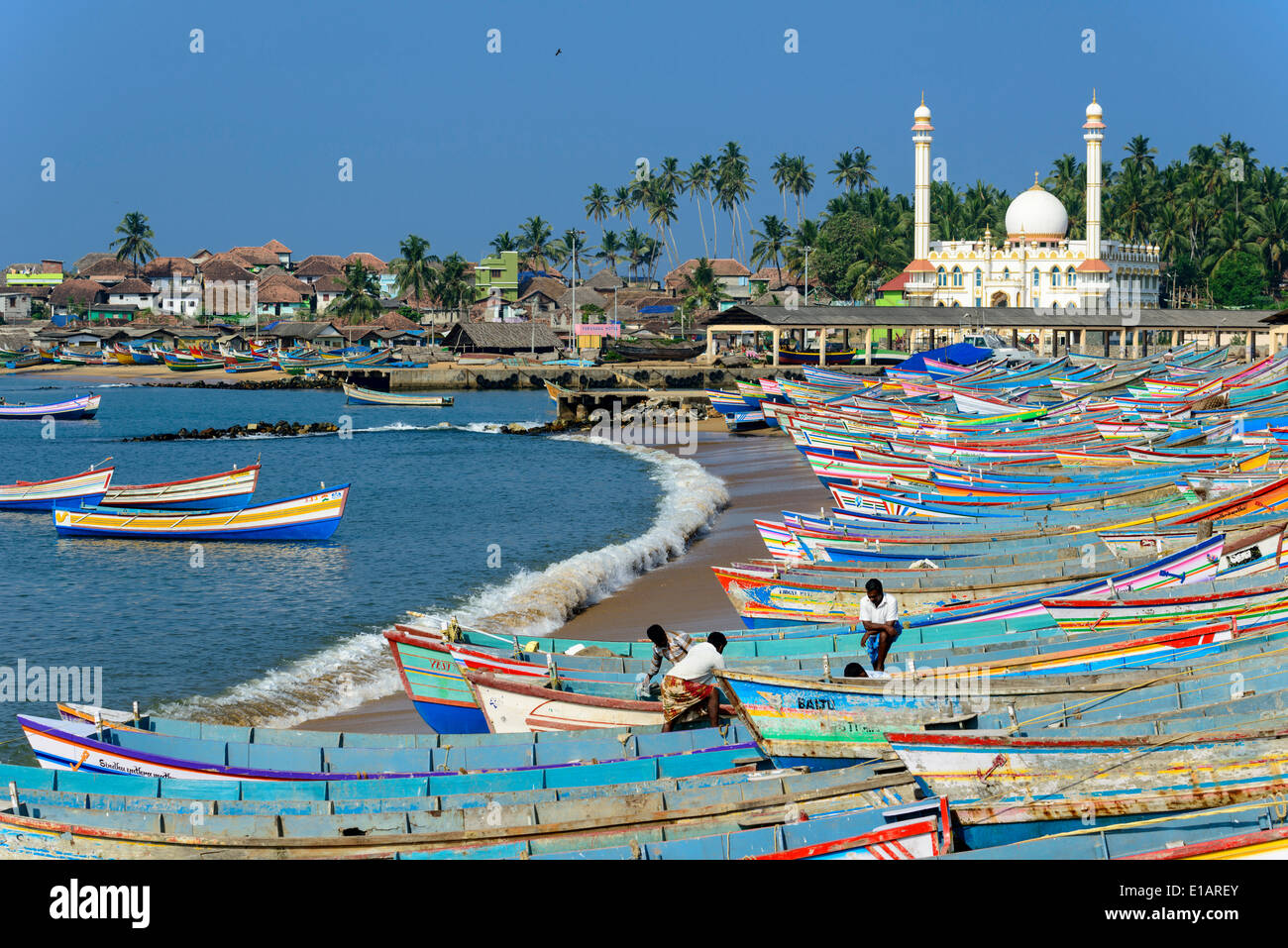 Colorful fishing boats in the harbour, Mohijedin Palli mosque at the back, Vizhinjam, Kerala, India Stock Photo